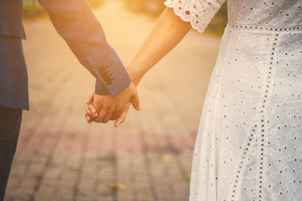 couple holding hands with sunlight  in park