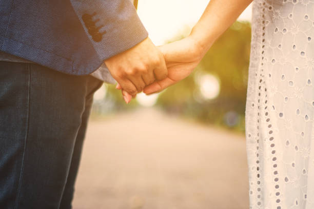 istock couple holding hands with sunlight  in park 859430720