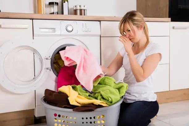 Photo of Woman Unloading Smelly Clothes From Washing Machine
