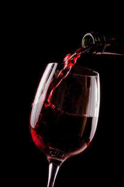 red wine pouring in wineglass from a bottle on black background. wine list design menu with copyspace. - wineglass red wine wine liquid imagens e fotografias de stock