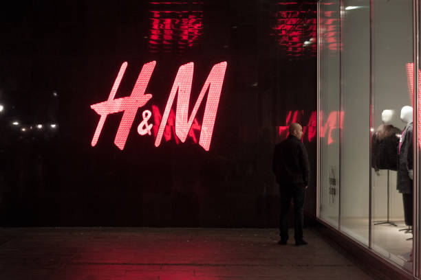 Man looking at the window of an H&M store in the Serbian capital city, a giant logo of H&M can be seen in background Picture of the logo of H&M taken in Serbia, with a client in front. H & M, or Hennes & Mauritz is a Swedish multinational clothing-retail company, known for its fast-fashion clothing. h and m stock pictures, royalty-free photos & images