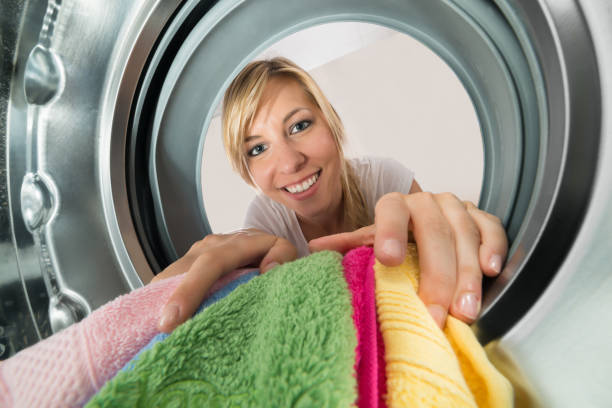 istock Smiling Woman Inserting Clothes In Washing Machine 859434880