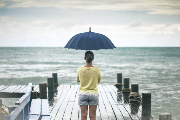 istock a young girl on a pier with an umbrella 859438288