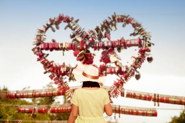 Asian woman take a photo by smart phone a Love padlocks by keys at Langkawi SkyCab, Malaysia.