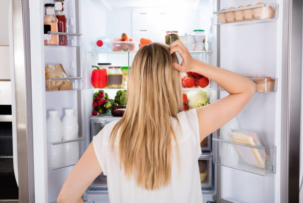vista posteriore della donna che guarda in frigo - frigorifero foto e immagini stock