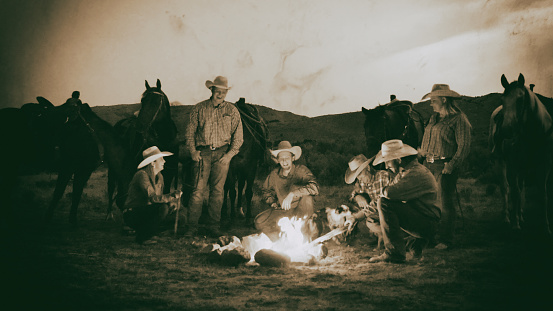 Cowboys and Cowgirls outdoors around the campfire in the west.