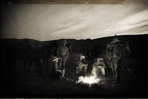Cowboys and Cowgirls outdoors around the campfire in the west.