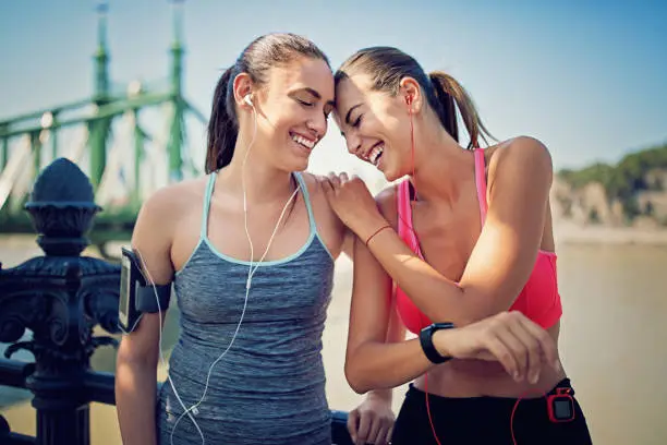 Photo of Runner girls are resting along the river and making fun together