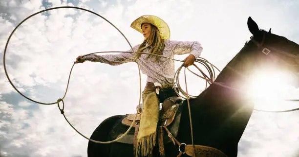 Little girl on horse with rope lasso.