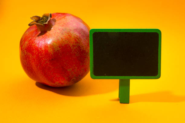Blank price board with pomegranate on orange background.
