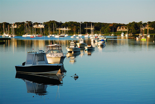 Calm waters reflect the clamming and recreation boats at Wychmere Harbor in Cape Cod