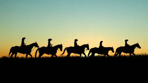 Photo of Cowboys on Horseback at Sunset