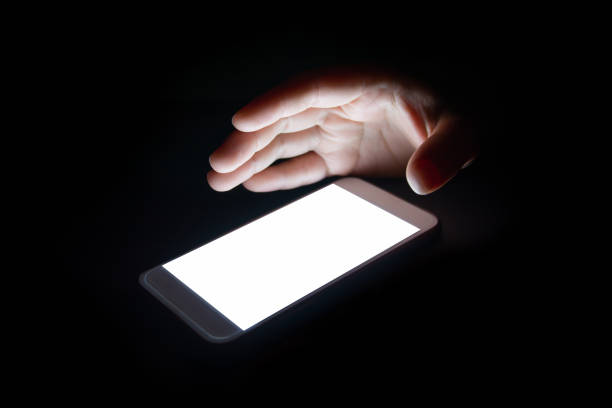 istock white light from the smartphone reflect your hand at night in the dark.blank screen for text and design 859478548