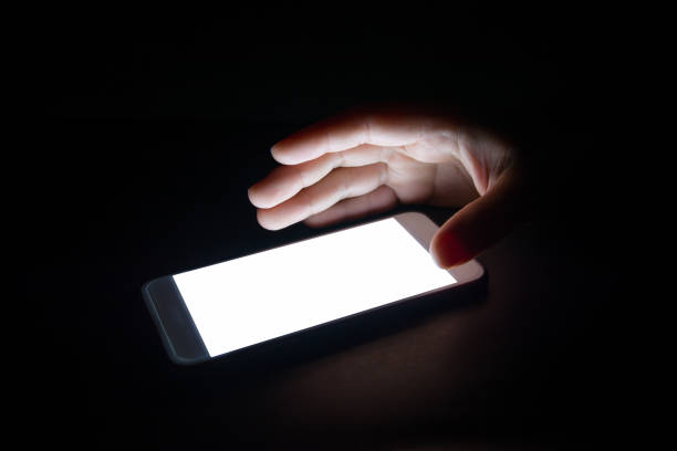 istock white light from the smartphone reflect your hand at night in the dark.blank screen for text and design 859478630