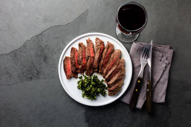 Medium rare beef steak served on white plate with red wine