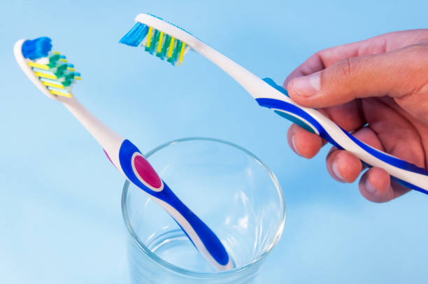 istock Two toothbrushes in a glass. A man's hand takes one toothbrush 859488936