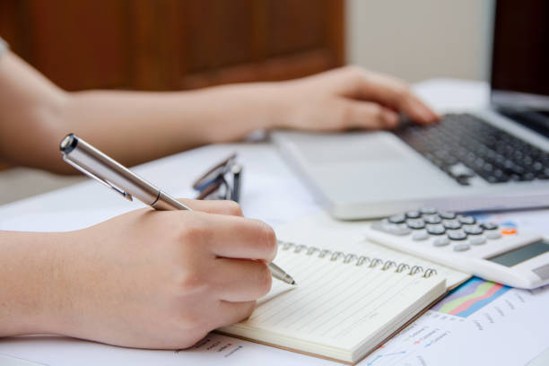 istock woman writing make note and useing laptop finance at home office. 859497434