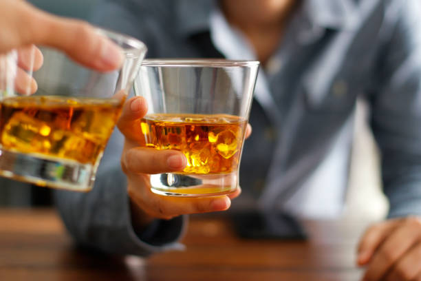 primer planos dos hombres tintinear vasos de whisky beben bebidas alcohol juntos en el mostrador en el pub - clunking fotografías e imágenes de stock