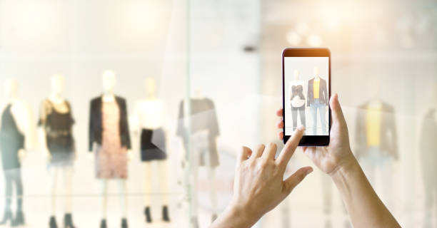 mani che usano lo smartphone mobile e scattano una foto in vista di un negozio di abbigliamento, concetto di shopping online - guardare le vetrine foto e immagini stock