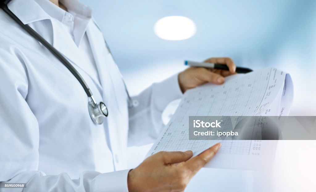 Medico donna che controlla e legge i rapporti finali in sala di lavoro di un ambiente ospedaliero - Foto stock royalty-free di Tabella