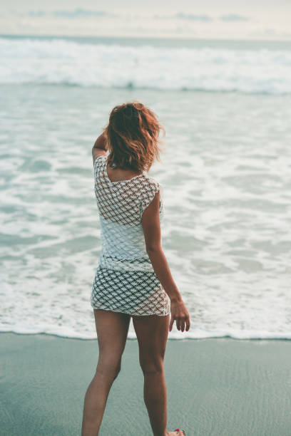 istock Sensual Female Goes Toward Wavy Ocean at Sunset 859504596