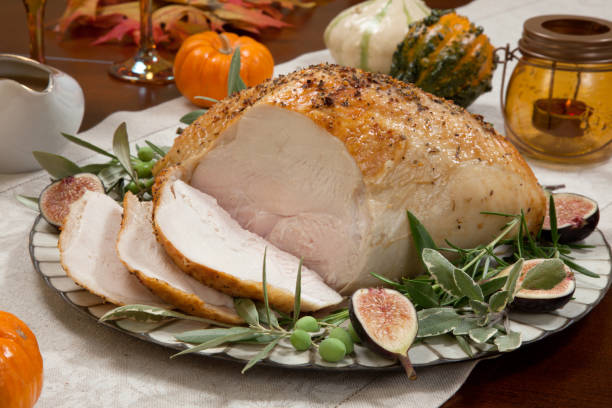 Carving Mediterranean Style Whole Roasted Turkey Breast Carving whole roasted turkey breast, Mediterranean style, garnished with fresh figs, olives, and herbs. Surrounded by pumpkins, candles, red wine, and ornaments. Thanksgiving theme."n carving food photos stock pictures, royalty-free photos & images