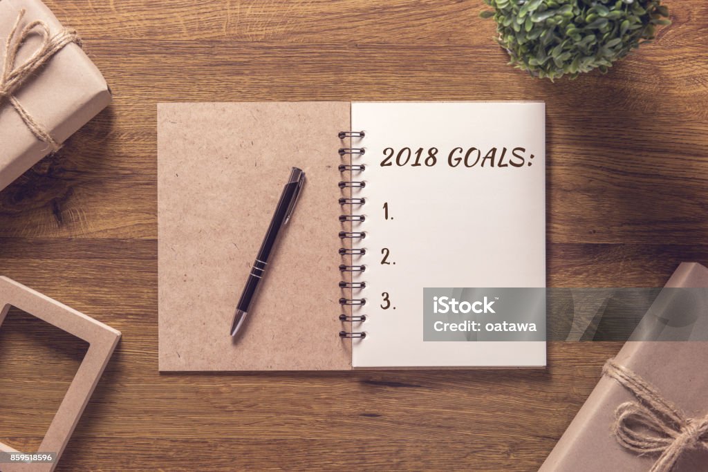 2018 goals list in notebook with gift box new year on wooden table background. Success Stock Photo