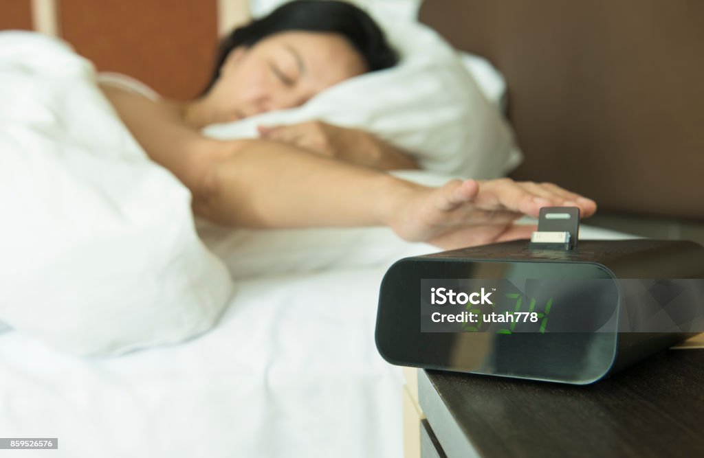 turn off the digital alarm clock Young woman reach out one's hand Press the button to turn off the digital alarm clock in morning. Alarm Clock Stock Photo