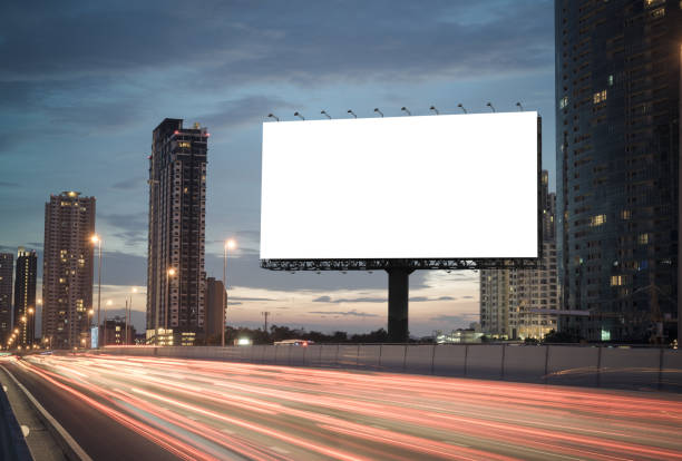 Blank billboard on the highway Blank billboard on the highway during the twilight with city background with clipping path on screen.- can be used for display your products or promotional publicity event stock pictures, royalty-free photos & images