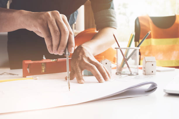 istock Engineer or Architect concept, Image of engineer drawing a blue print design building or house, An engineer workplace with blueprints, pencil, protractor and safety helmet, Industry concept 859540380