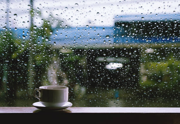雨の日の木製テーブルでホットド リンクのカップ - 雨 ストックフォトと画像