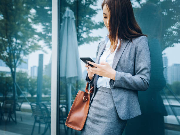 istock business woman leaning on glass wall using smartphone 859547710