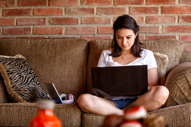 испаноязычная молодая женщина, работающая на ноутбуке дома. концепции домашнего офиса - shorts women people young women стоковые фото и изображения
