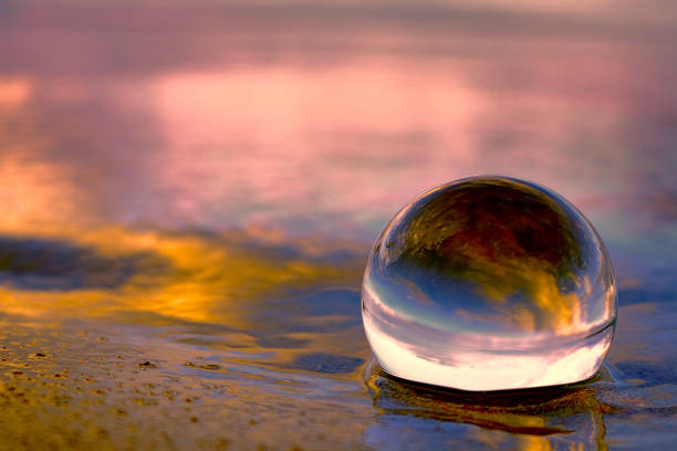 puesta de sol que refleja en una bola de cristal en la playa - paz mundial fotografías e imágenes de stock