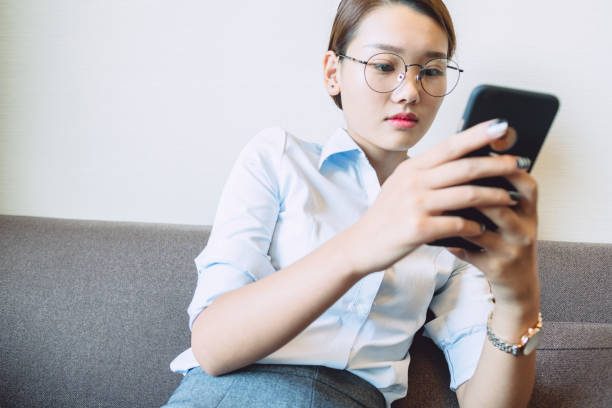 istock side view of woman sitting on sofa using smartphone 859553840