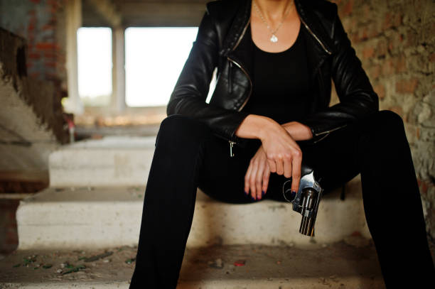 beautiful secret agent in black dress holding gun, isolated on white