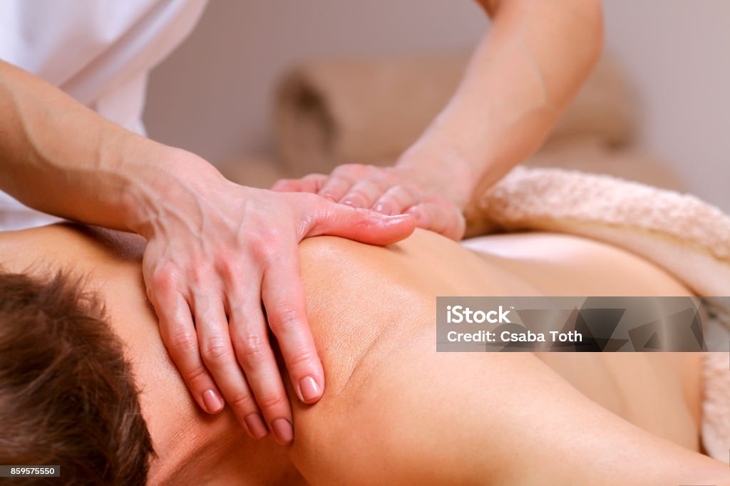 Massage therapist massaging shoulders and back of a male Young man receiving shoulder and back massage from therapist in spa Massage Therapist Stock Photo