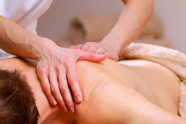Massage therapist massaging shoulders and back of a male stock photo
