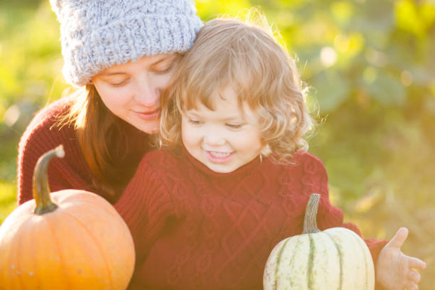 istock Mother and child choosing pumpkins for jack-o-lantern. 859576302
