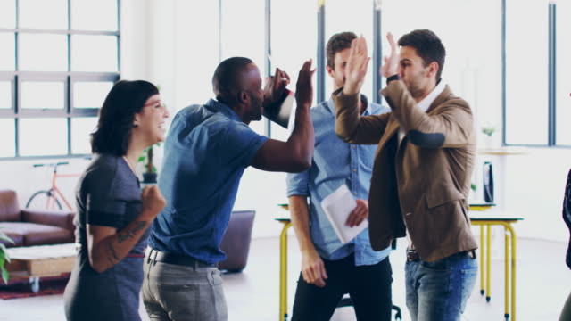 4K video footage of a group of coworkers cheering and celebrating success in a modern office