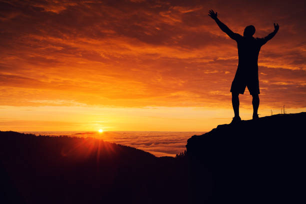 istock Man silhouette on the mountain top watching the sunrise over clouds 859587404