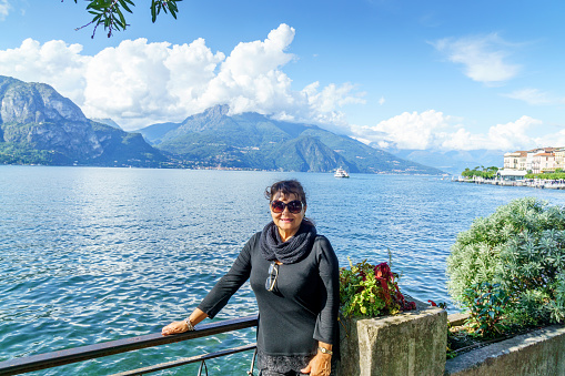 Attractive senior hispanic woman standing above Lake Como