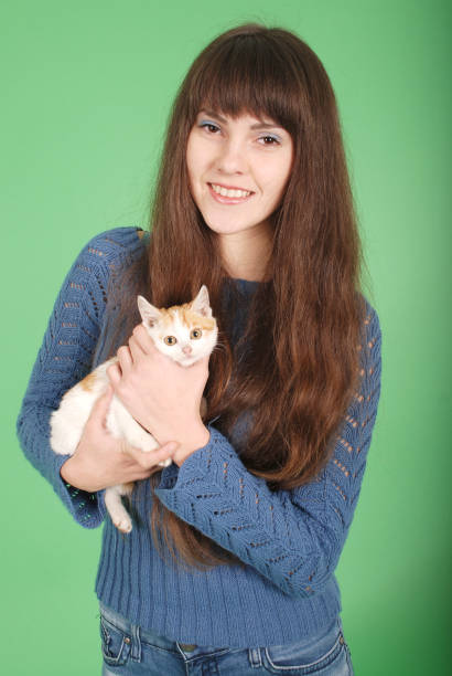Beautiful smiling brunette girl and her cat over green background