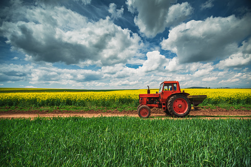 Red tractor in a field and dramatic clouds
