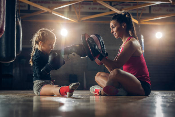 istock Young boxing coach practicing with small girl in a gym. 859599660