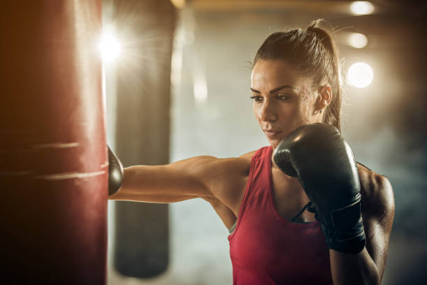 istock Athletic woman punching boxing bag during sports training. 859603312