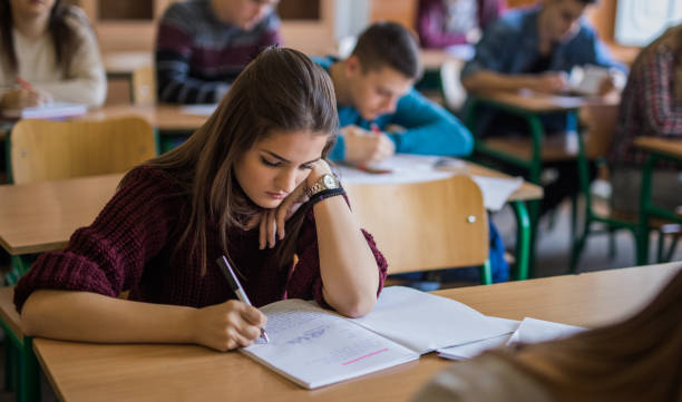 istock Teenage girl writing a lecture in a notebook during class. 859604816