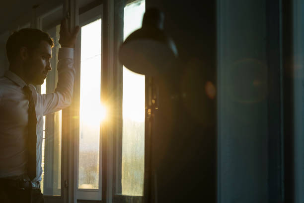 istock Businessman looking through the window at sunset 859612620