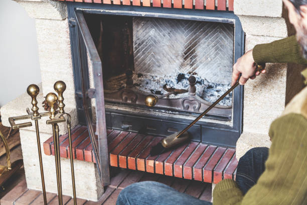 man cleans fireplace with brush and blades stock photo
