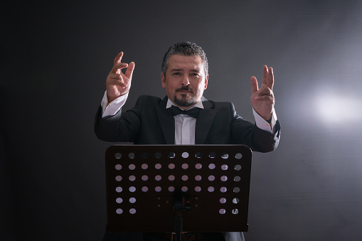 Studio photo of music conductor over black background